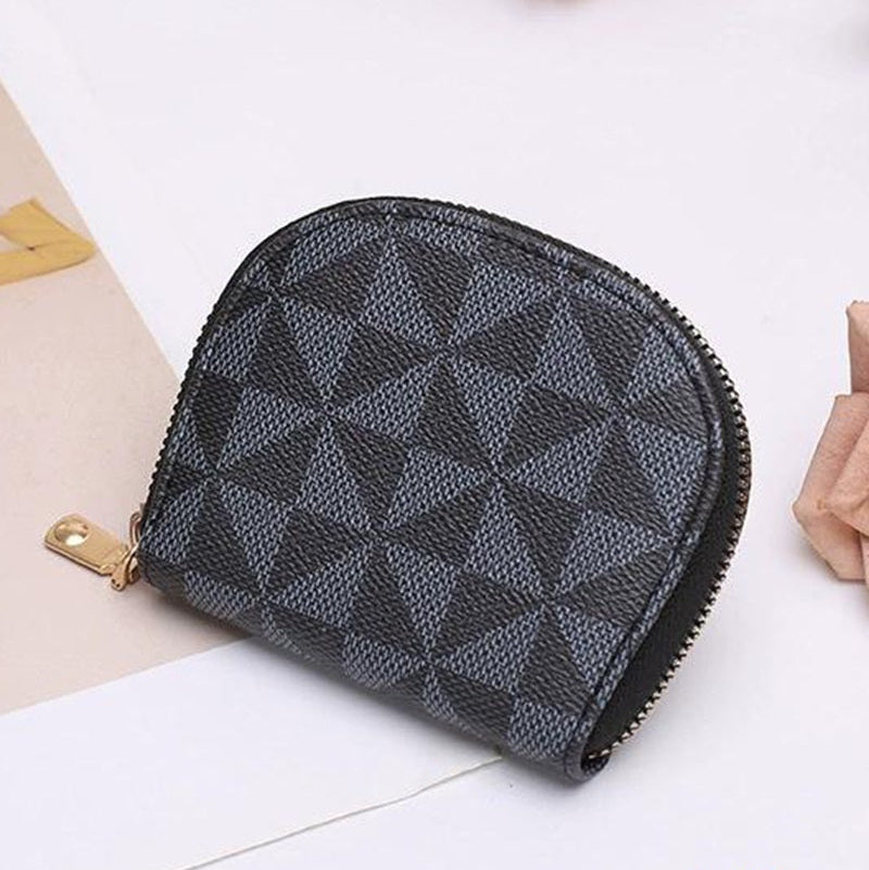 Black geometric patterned pouch on a white surface with flowers and a book in the background.