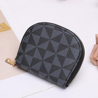 Black geometric patterned pouch on a white surface with flowers and a book in the background.