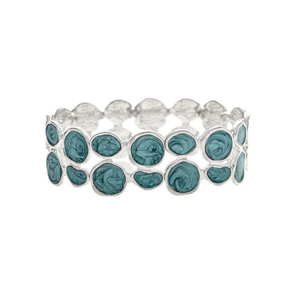 A silver stretch band bracelet featuring a row of oval-cut teal blue-green gemstones, set against a plain white background.