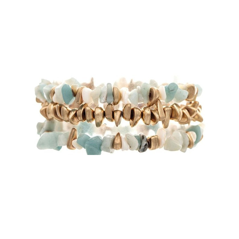 Three stacked stretch bracelets featuring light blue and white stone chips with metallic gold spacers, set against a plain white background.