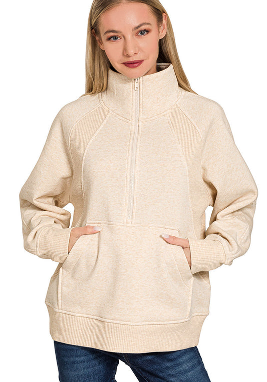 Woman wearing a beige zip-up hoodie with blue jeans on a white background