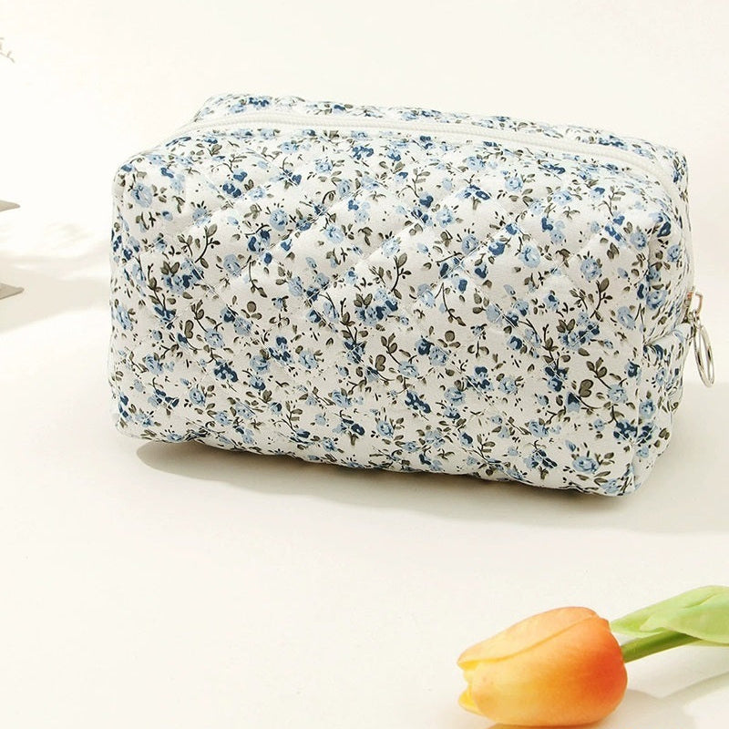 Floral-patterned toiletry bag on a white background with a tulip.