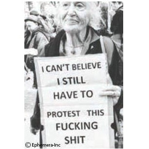Black and white photo of a person holding a protest sign with text.